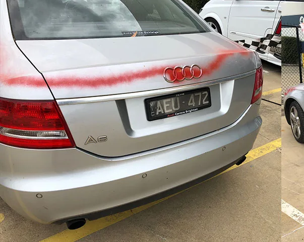 Red graffiti sprayed across the boot of a silver Audi
